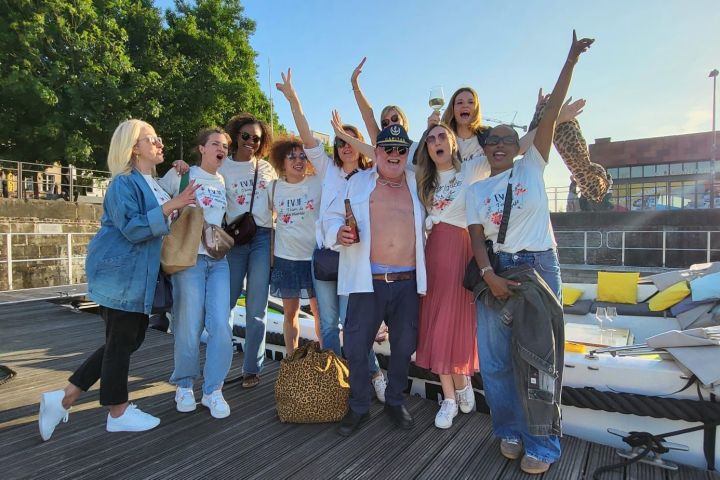 Group of people celebrating on a dock with a captain, near a boat, cheering and smiling.