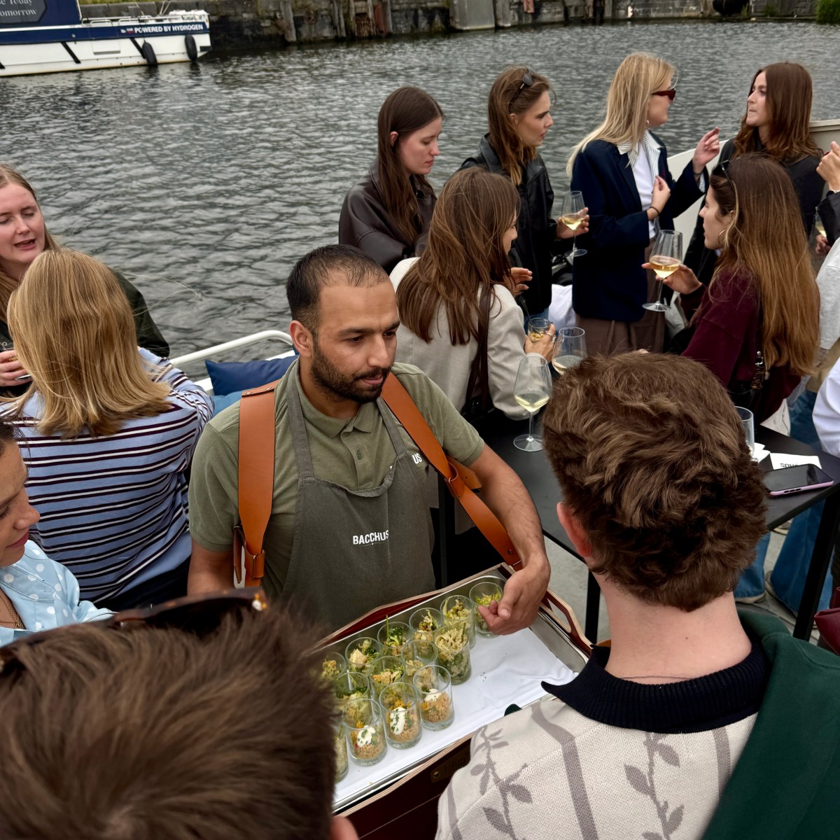 People socializing on a boat with drinks and appetizers.