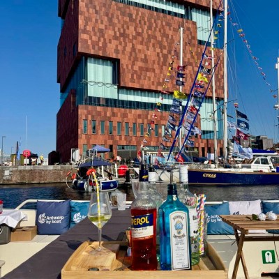 Drinks on a boat with a brick building and sailboats in the background.